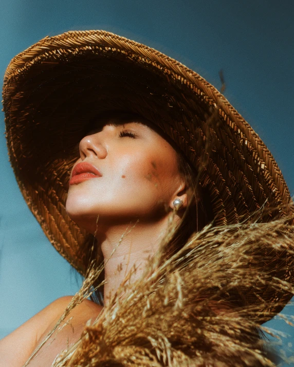 a woman with a straw hat standing by the ocean