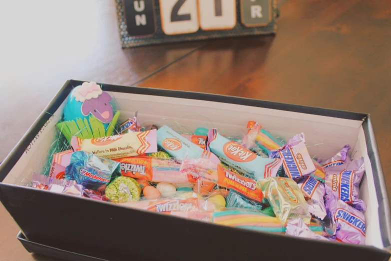 a cardboard box filled with candies and candy on a table