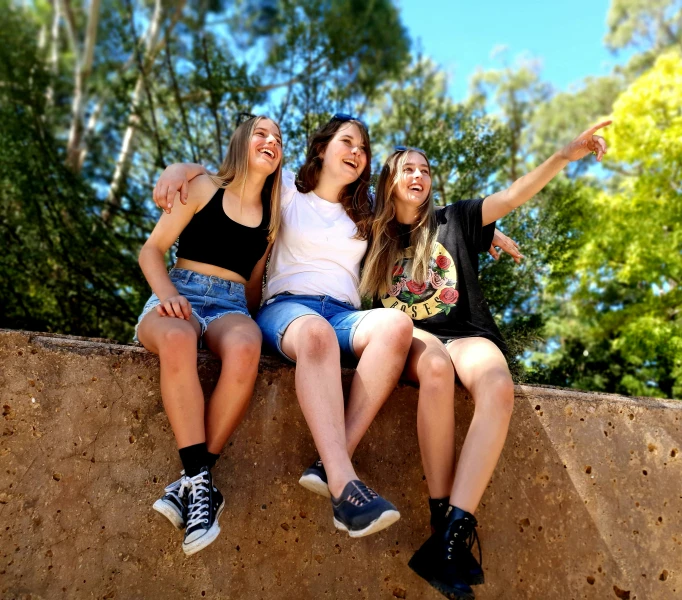 three women sitting and smiling, some leaning against a wall
