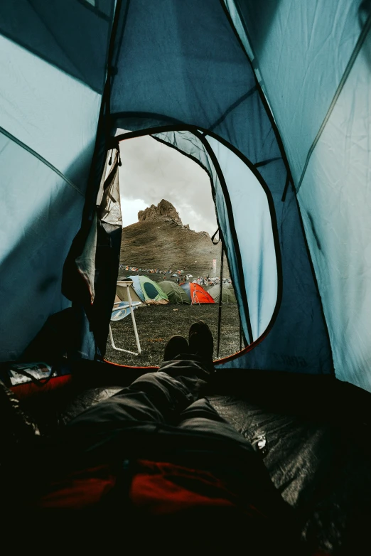 a person sitting inside of a tent while looking at the mountains