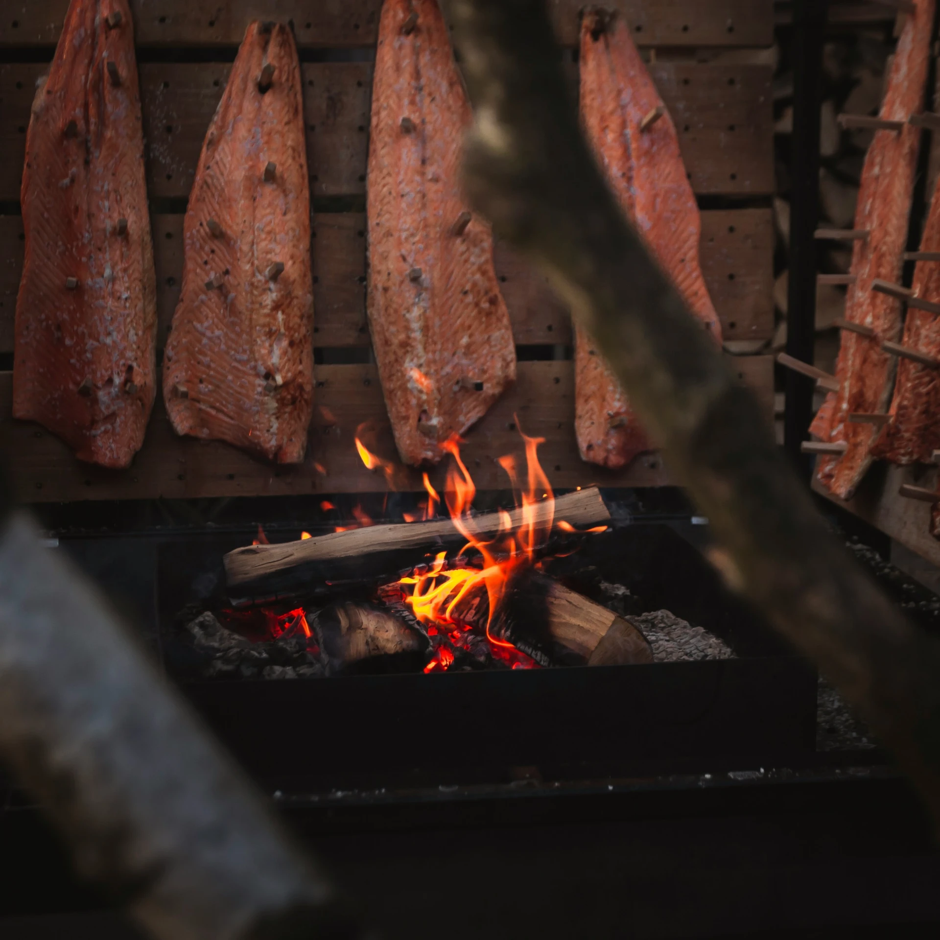 some meats roasting on the grill with a bright flame