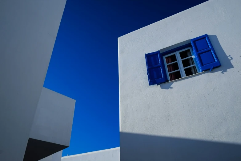 a building with blue windows on the side and blue skies above