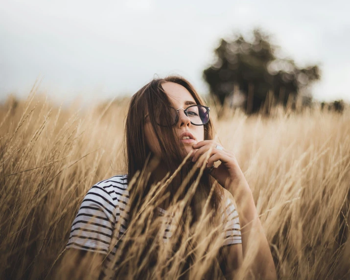 a woman sitting in tall grass with her eyes closed