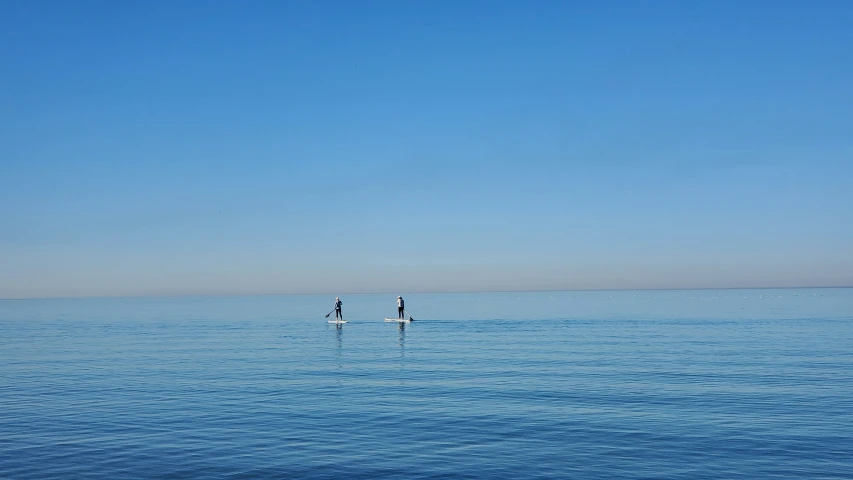 two surfboards out on the water under a clear blue sky