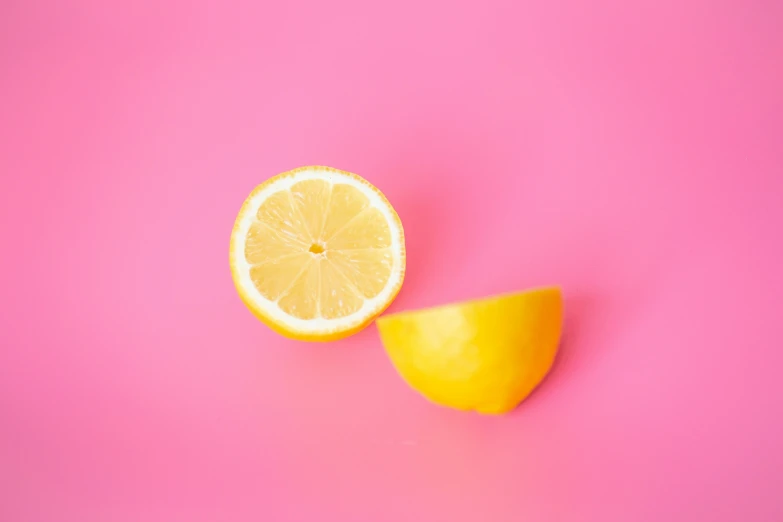 two halves of lemons sitting next to one another on a pink surface