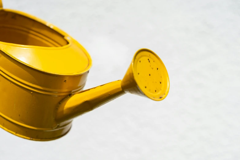 a plastic yellow watering can with a handle