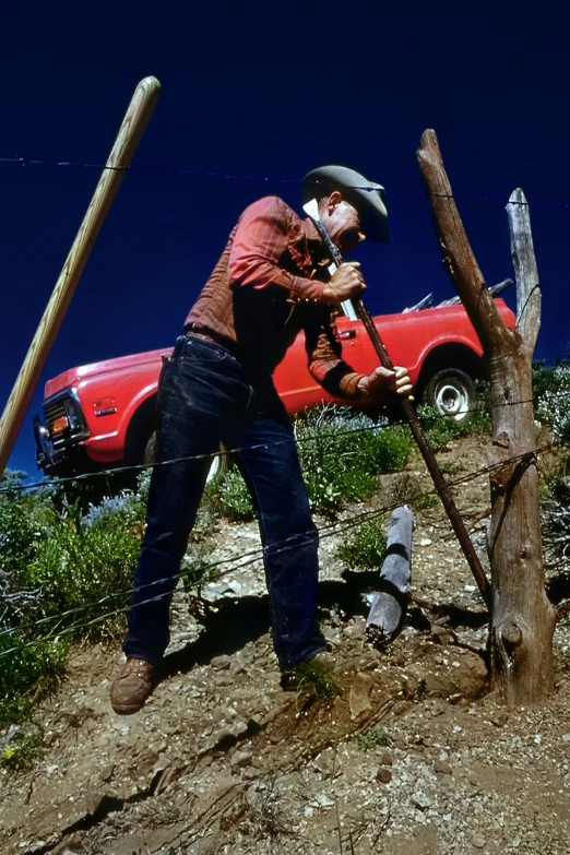 a man uses a power saw to cut down a tree trunk