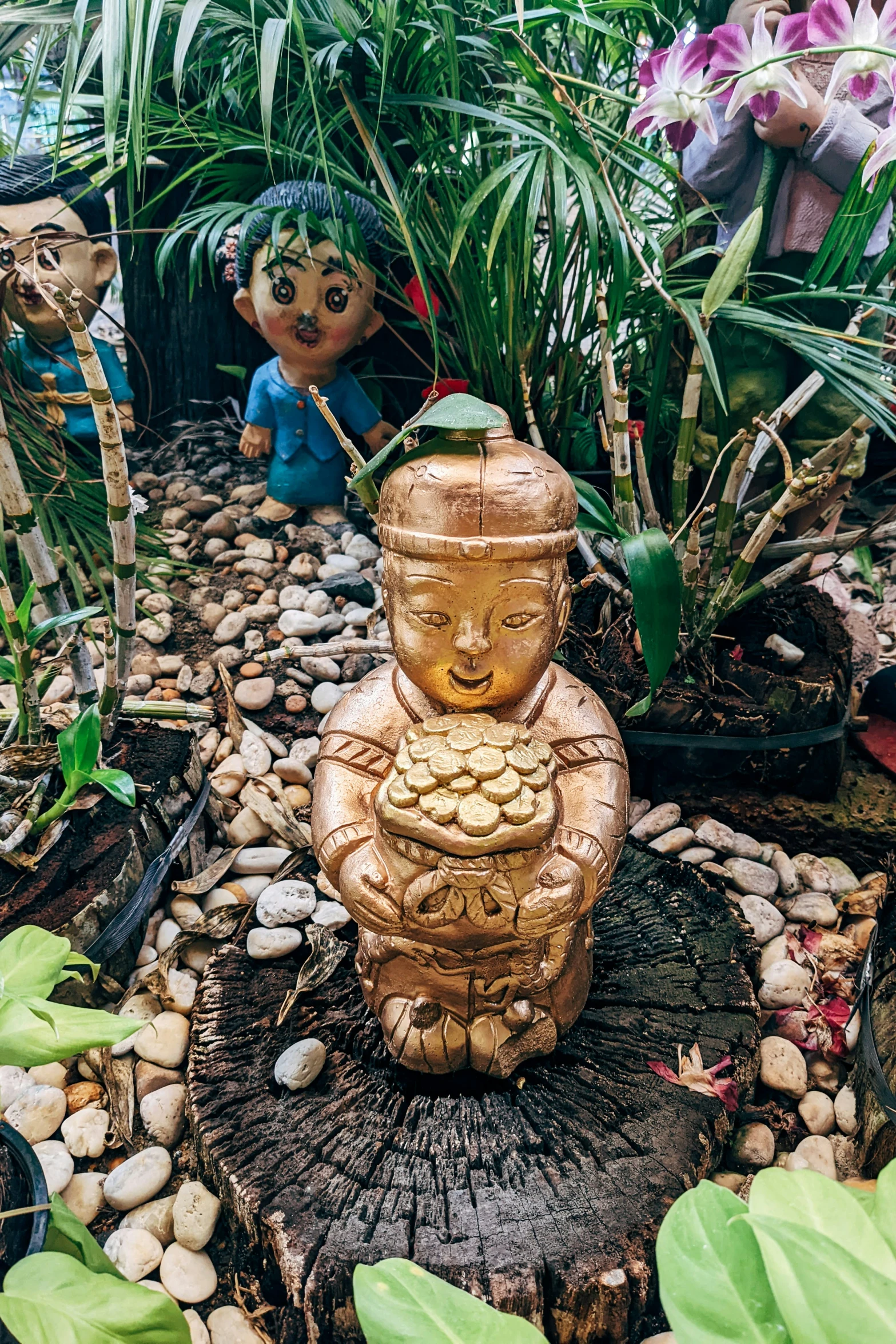 the small statue in the plant garden has a gold body