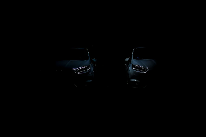 two cars are shown side by side in the dark