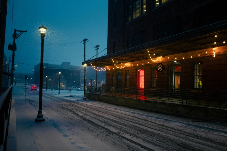 there is a snow covered street in front of some buildings