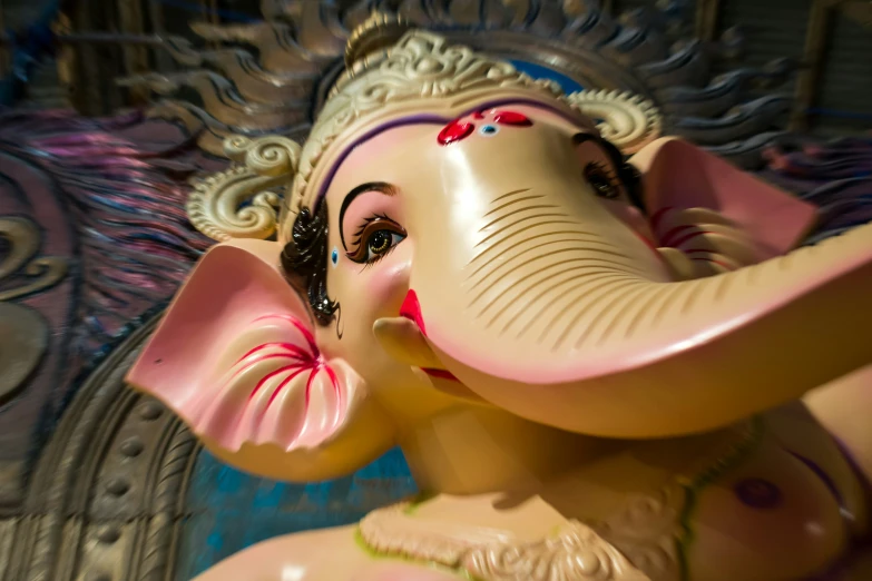 a statue of a small elephant with pink tusks and red ears