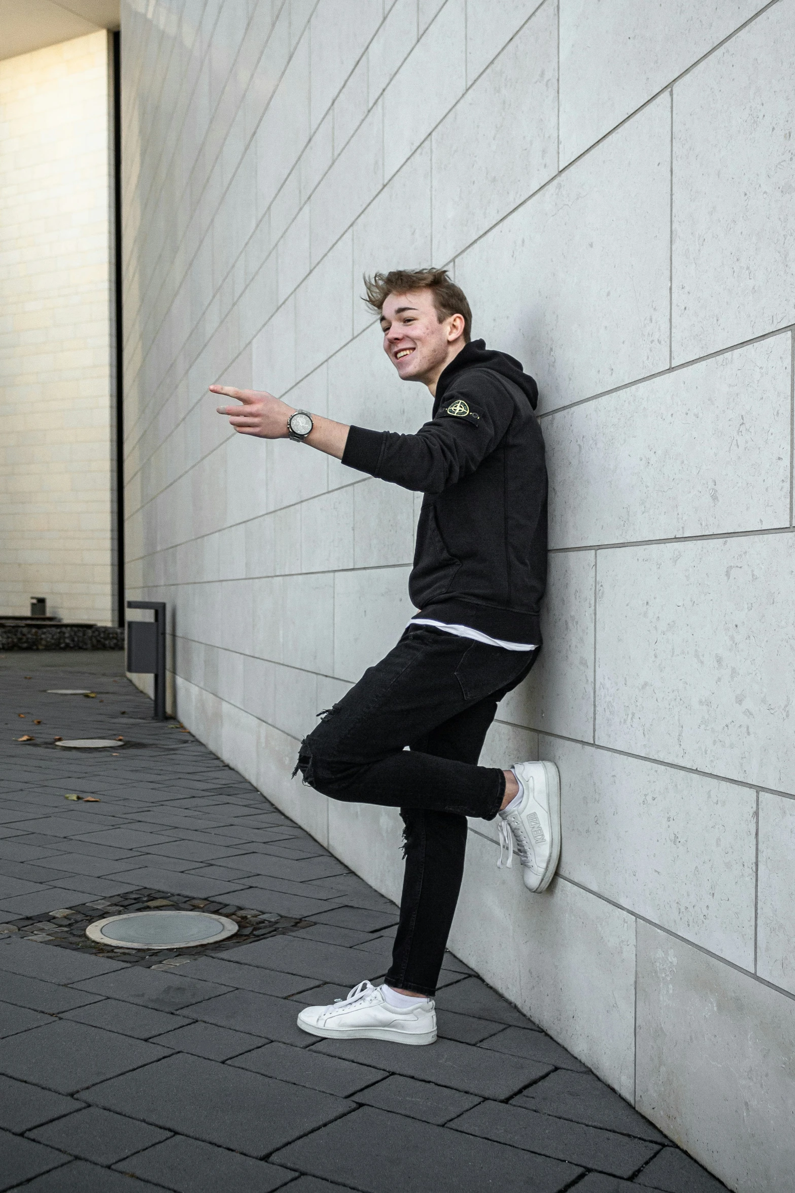 the young man in black is posing by a wall