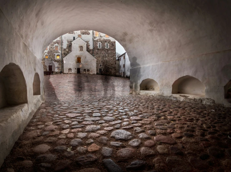 a cobblestone street with a arched stone wall