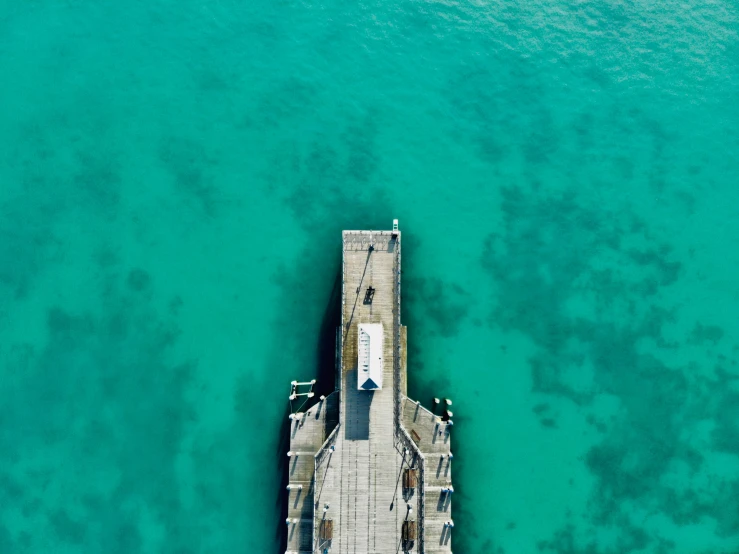 aerial view of pier in the middle of blue water