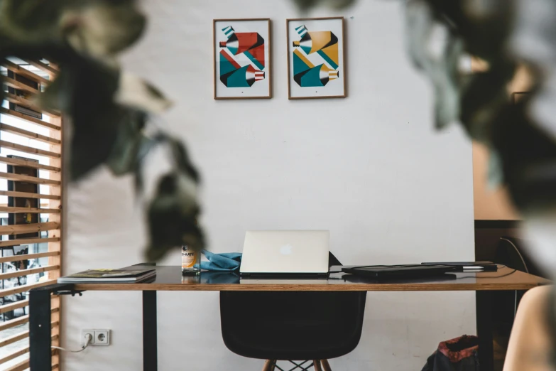 the view of a laptop on a table and two paintings