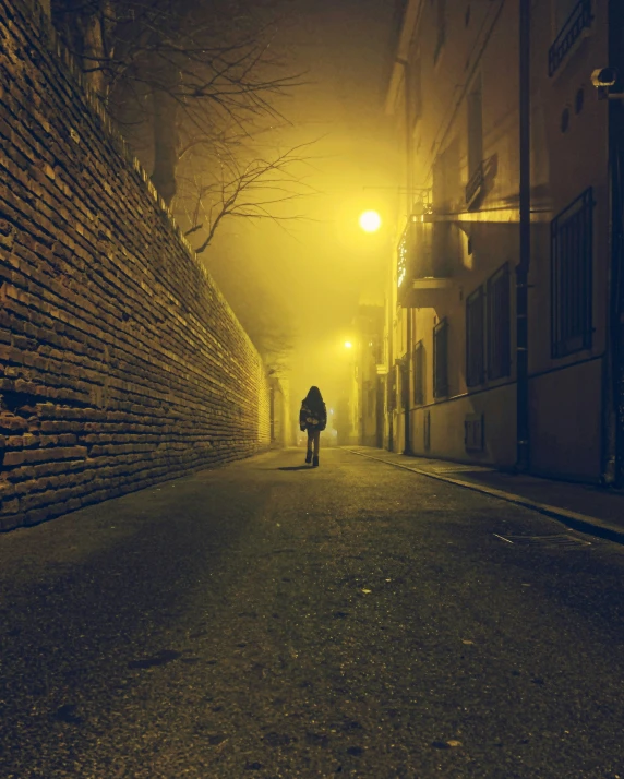 the person is walking down the alley in a dark street