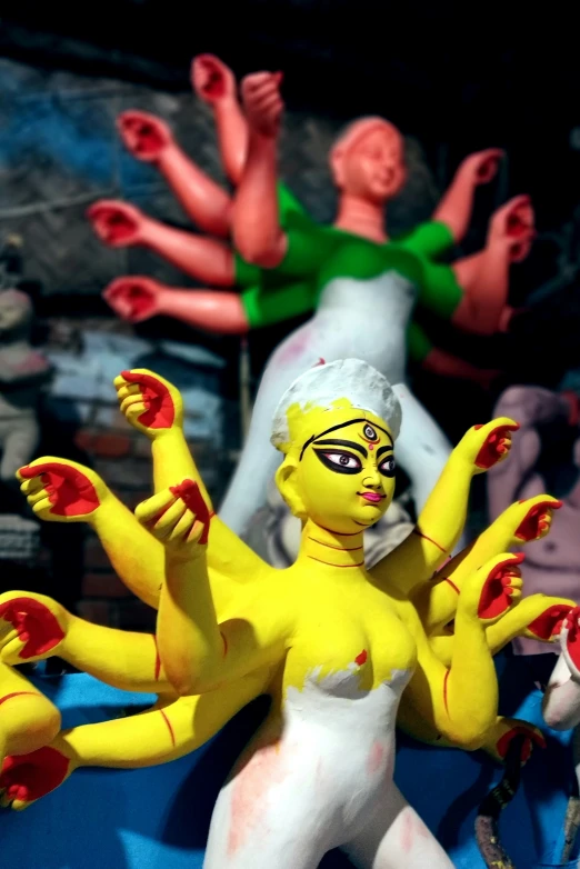 a yellow doll with two hands on it in the middle of figures