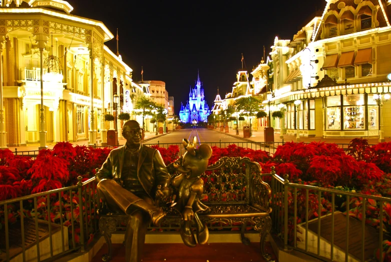 the statue of a man on a bike is displayed in front of red flowers