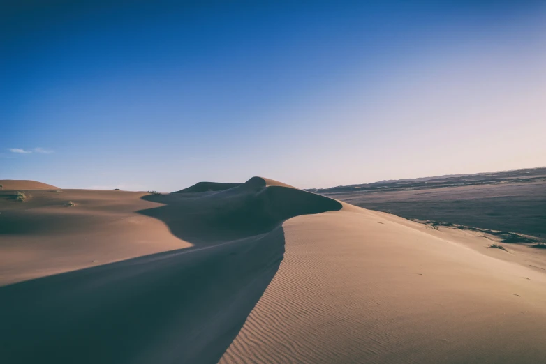 a small hill in the middle of sand dunes