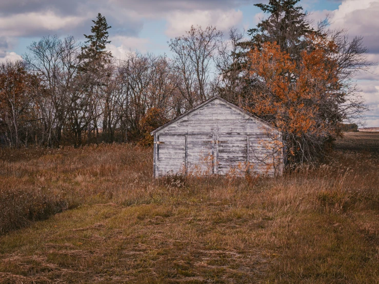 an old run down shed sitting out in a field