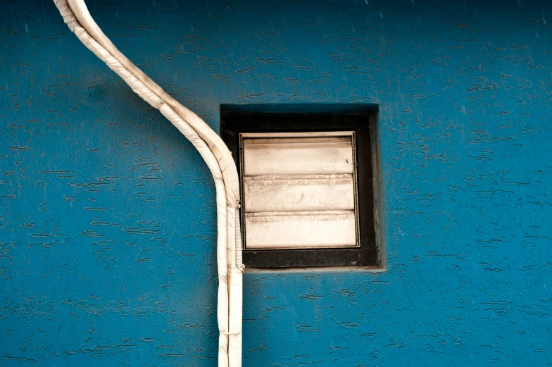 a window on a blue building near an iron pole