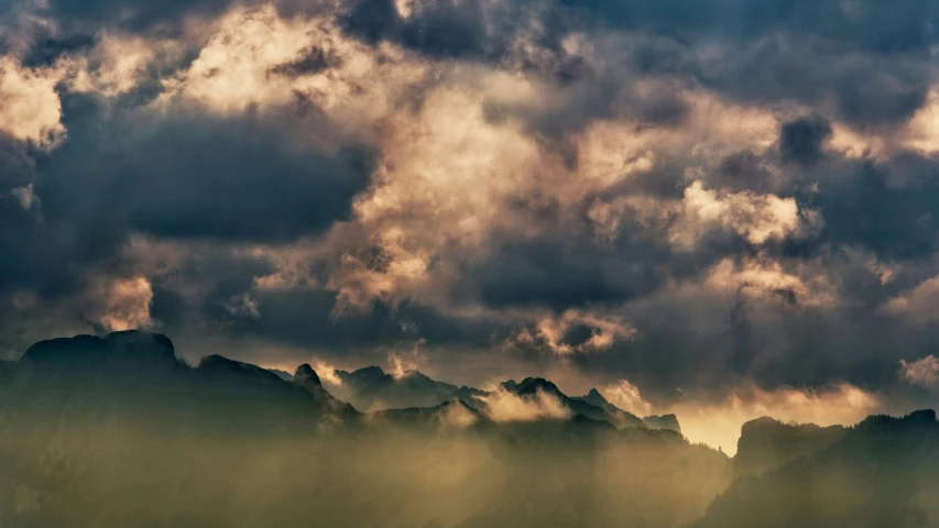 cloudy and dark storm clouds roll over mountains