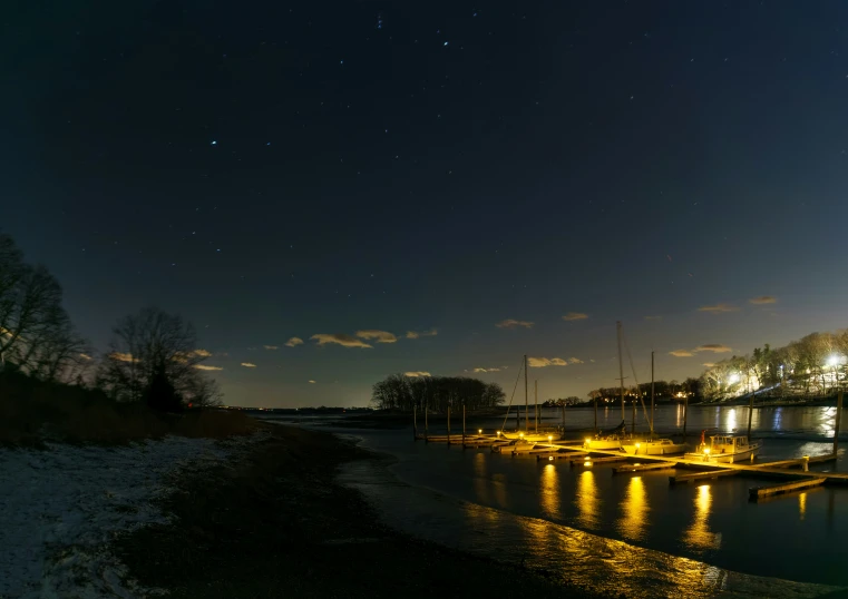 many boats on the water at night under a cloudy sky