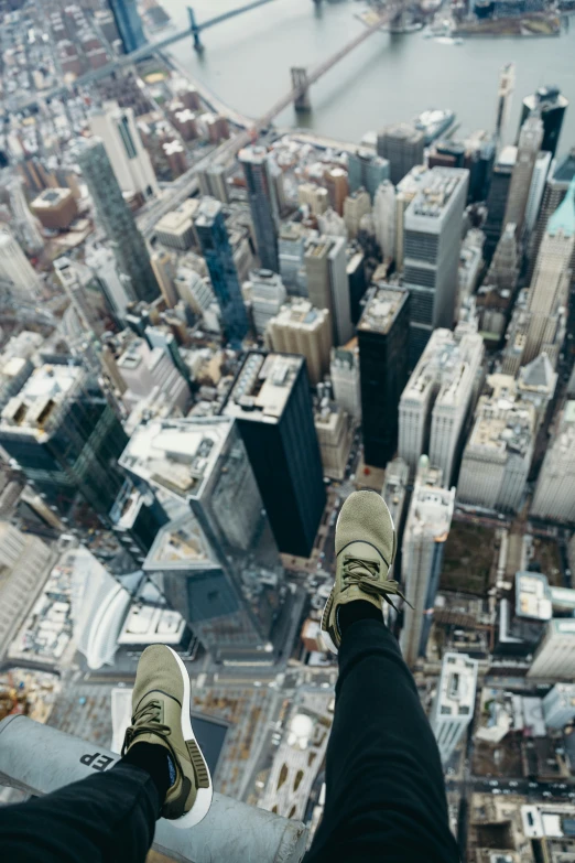 a person's feet and ankles standing on a ledge overlooking city