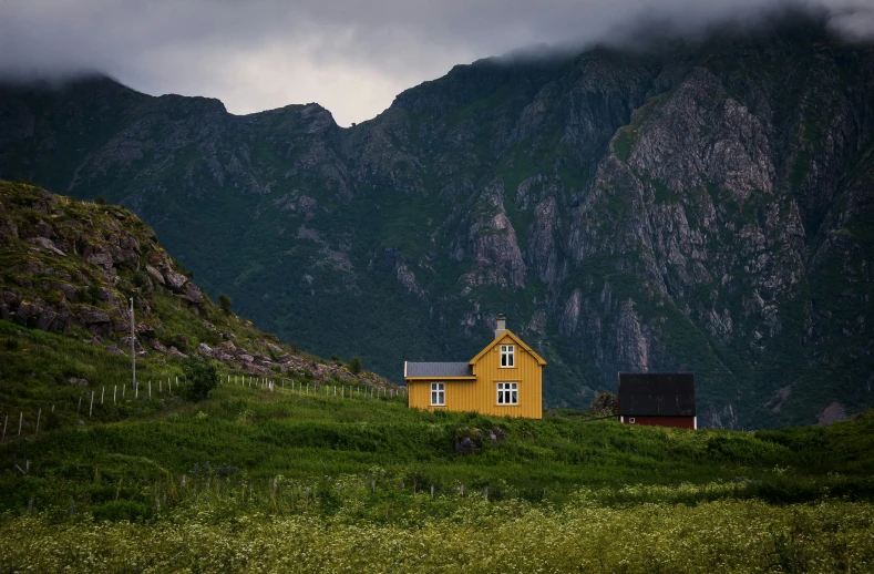 a small house sits near the mountain side