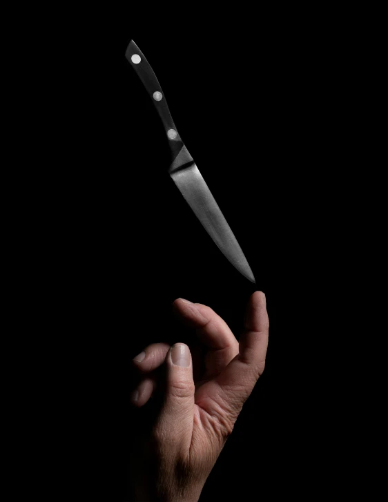 a knife being held over the top of the tip of a knife
