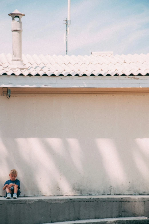 boy sitting on a cement ledge with his back against the wall