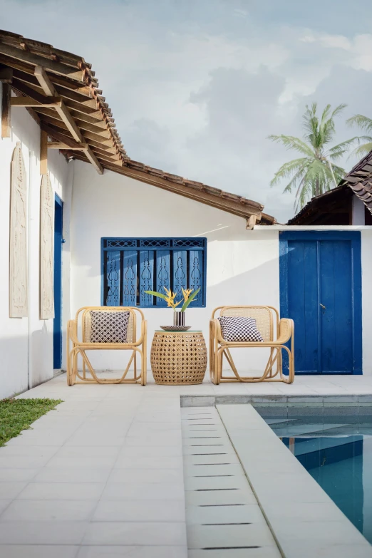 some brown rattan chairs a pool and some white walls