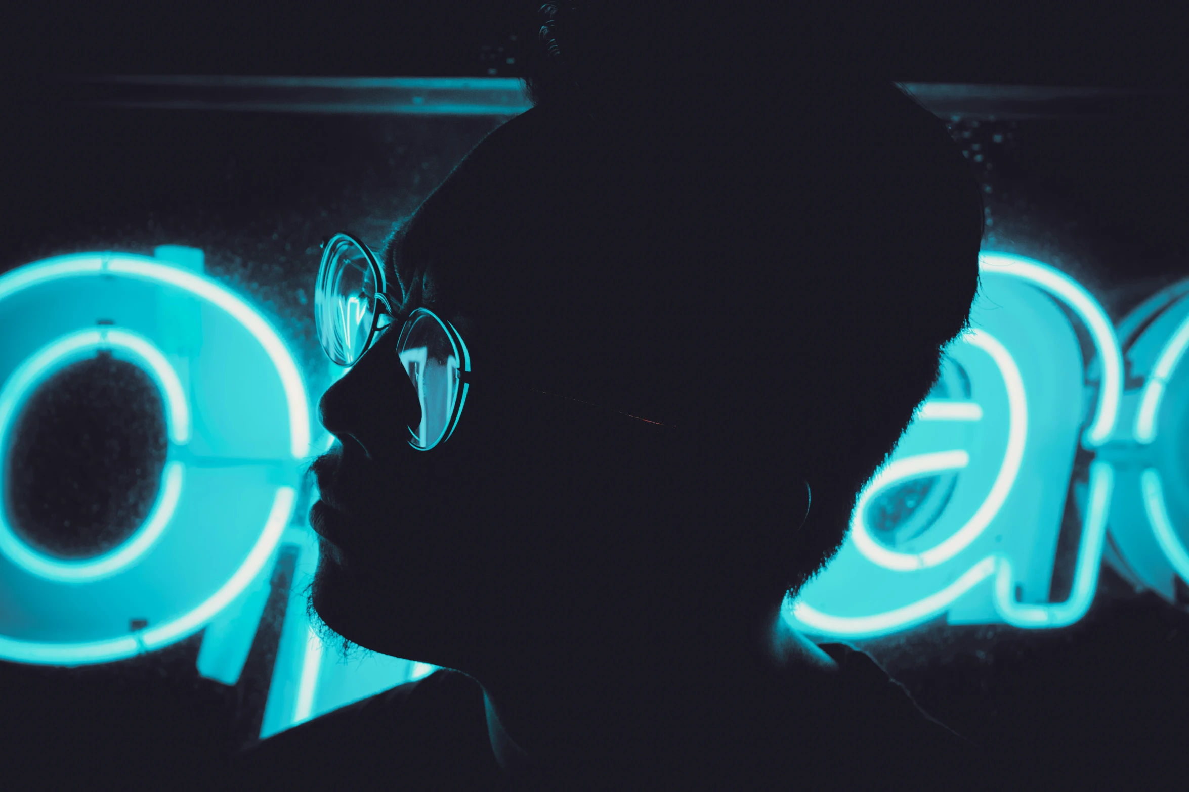 the silhouette of a person wearing a pair of glasses against a neon wall