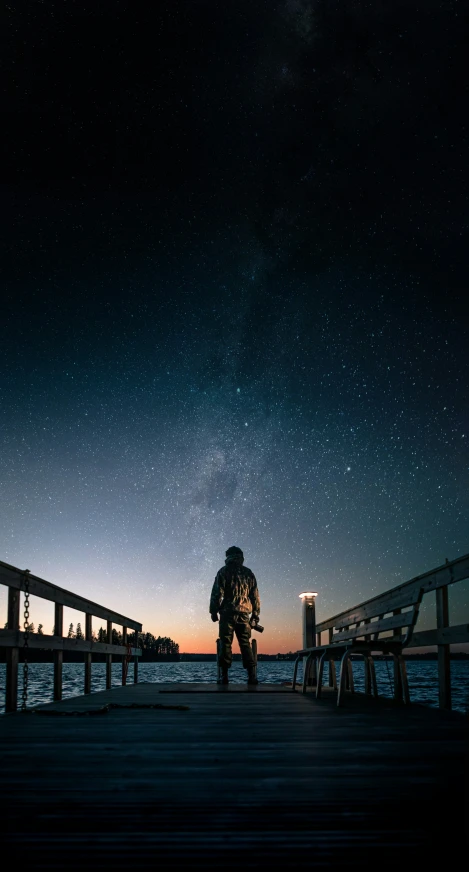 a person is sitting on a bench watching the stars