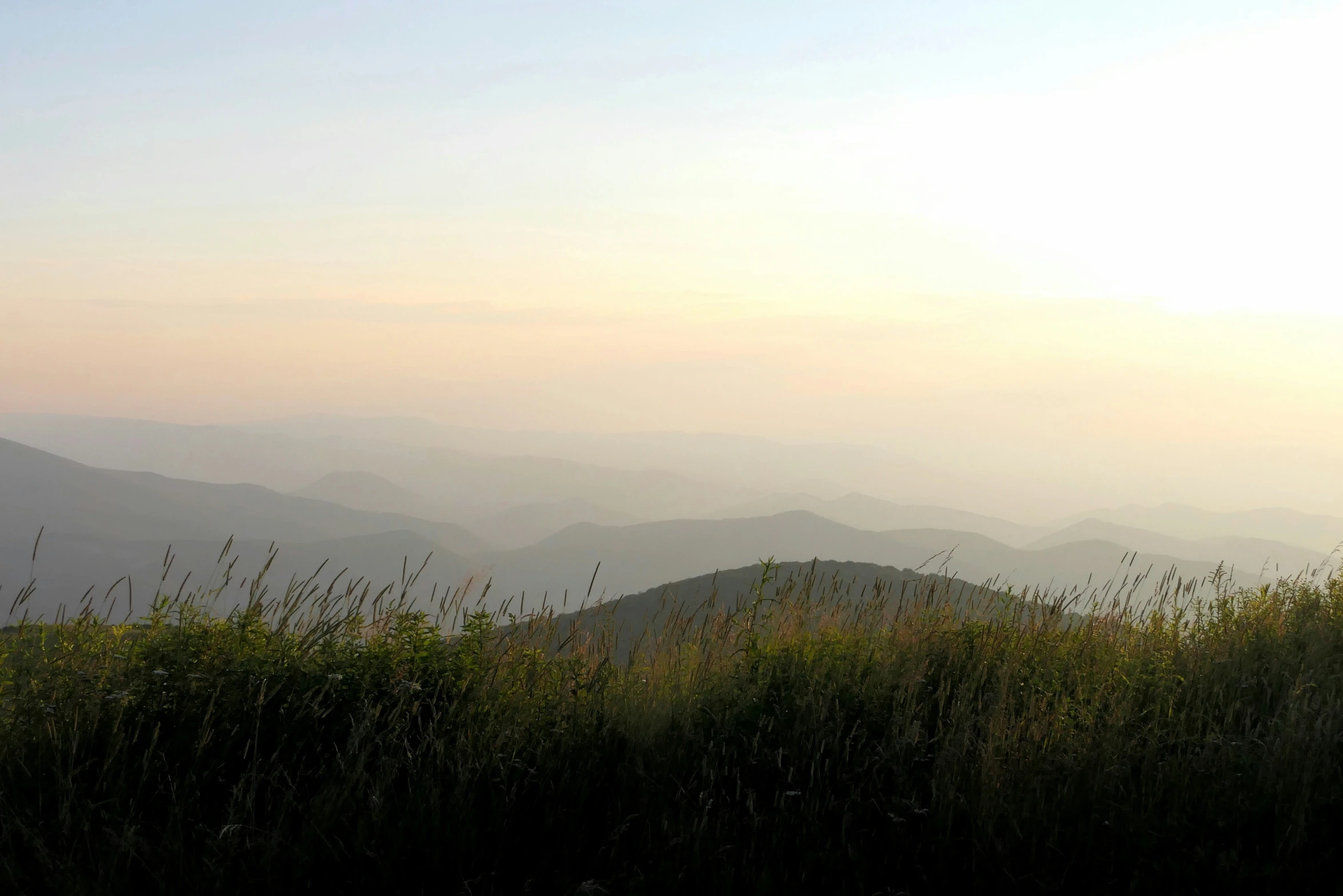 a sunset view from a ridge overlooking grassy terrain