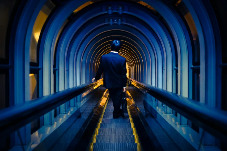 a man in a suit on escalator to an underground tunnel