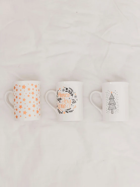 three matching coffee cups on white fabric