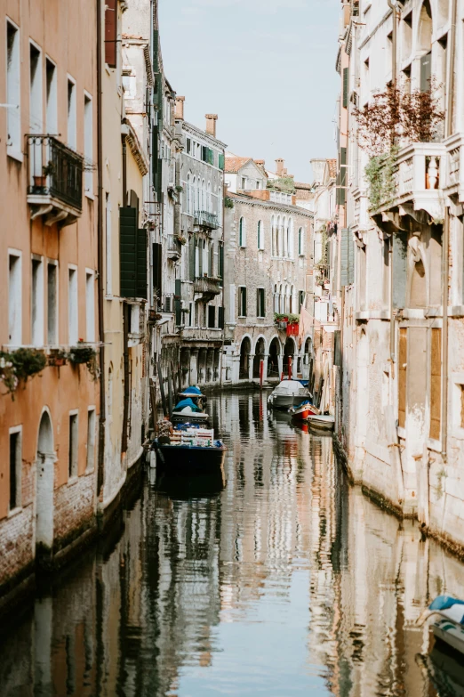 several boats float down a small canal between buildings