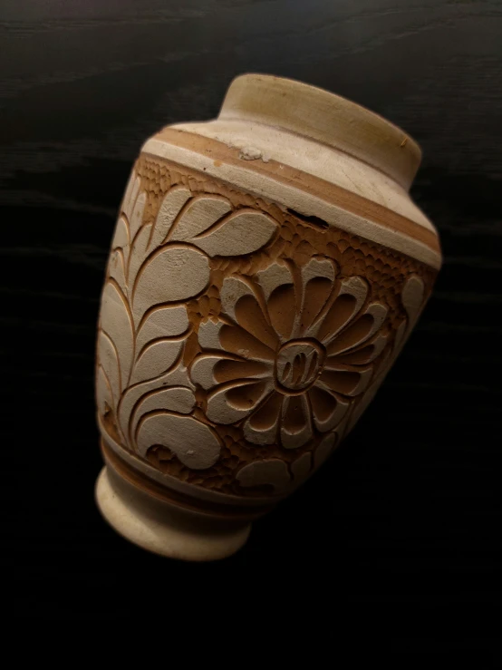 a white and brown vase with designs on it