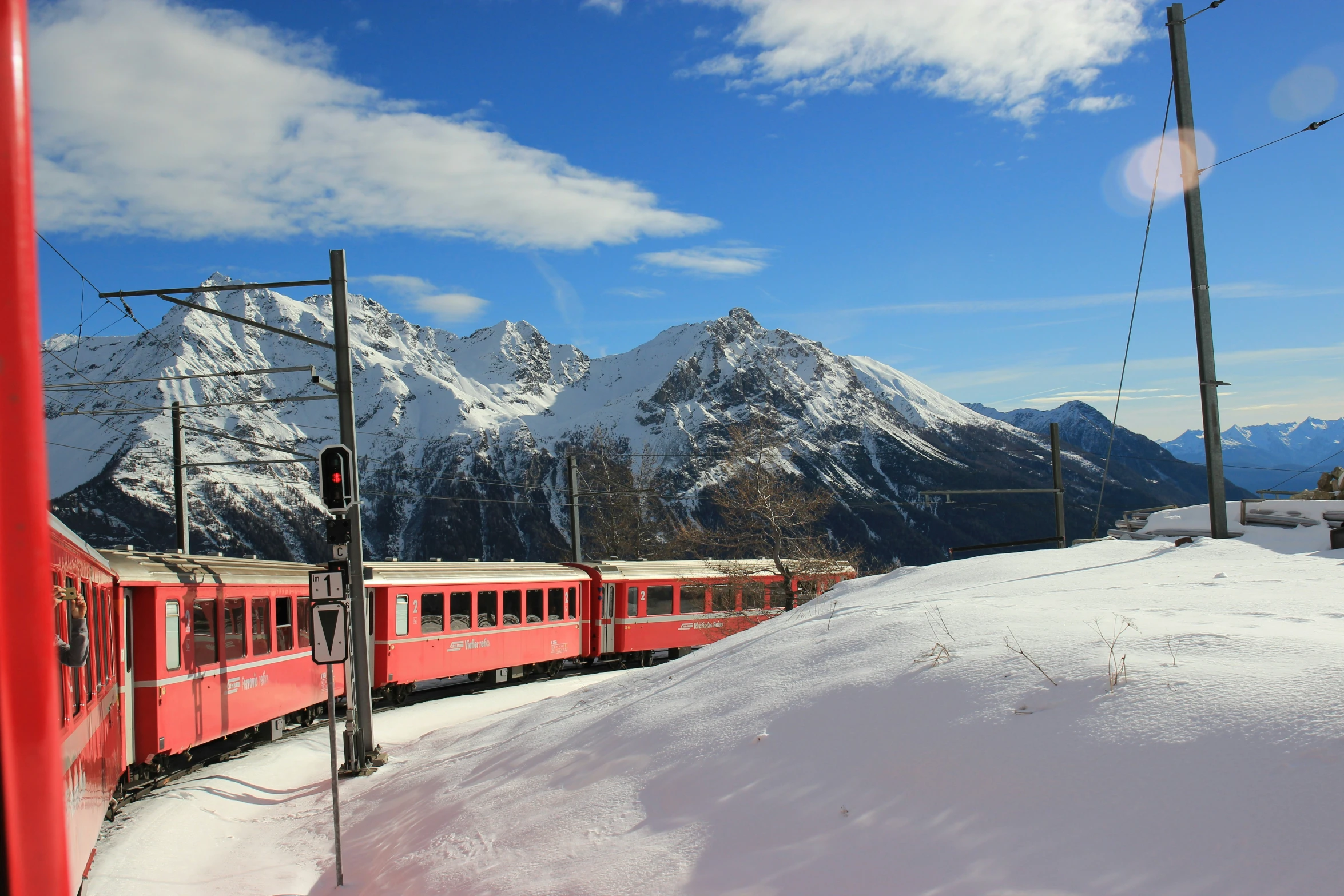 red train going through snowy mountains near lamp post