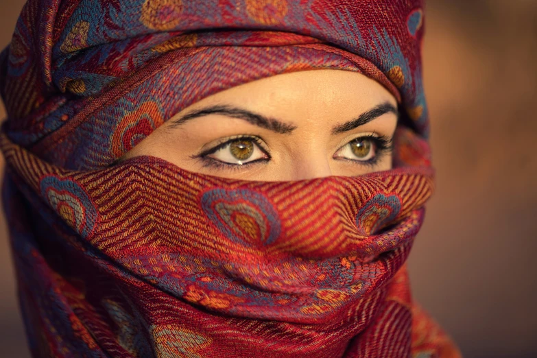 a close up of a person wearing a hijab and wearing green eyes