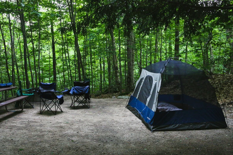 a blue tent set up on the dirt in a park area