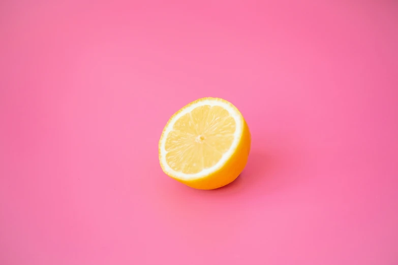 a yellow orange on pink background sliced in half