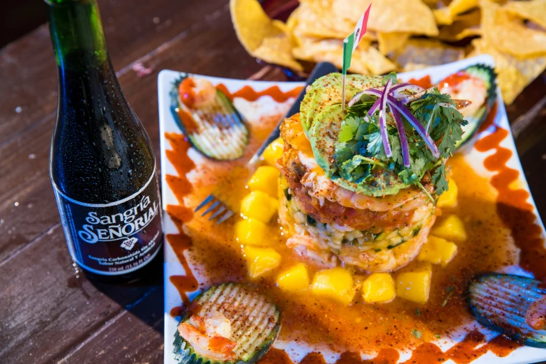 a small tower on a plate next to a bottle and chips