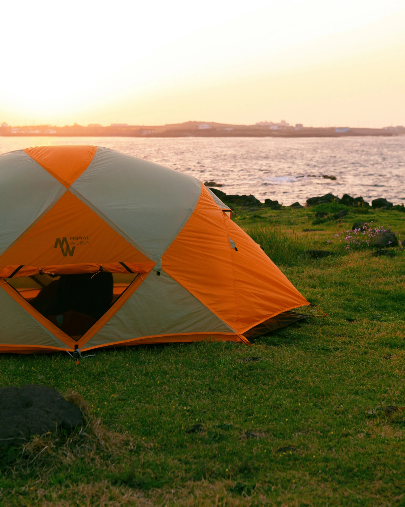 a tent with two large pieces of material on the ground, next to the water