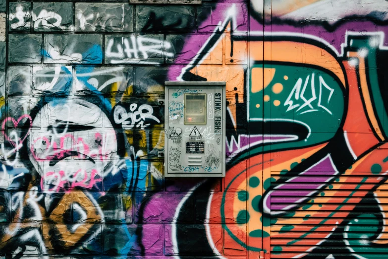 a parking meter in front of some graffiti