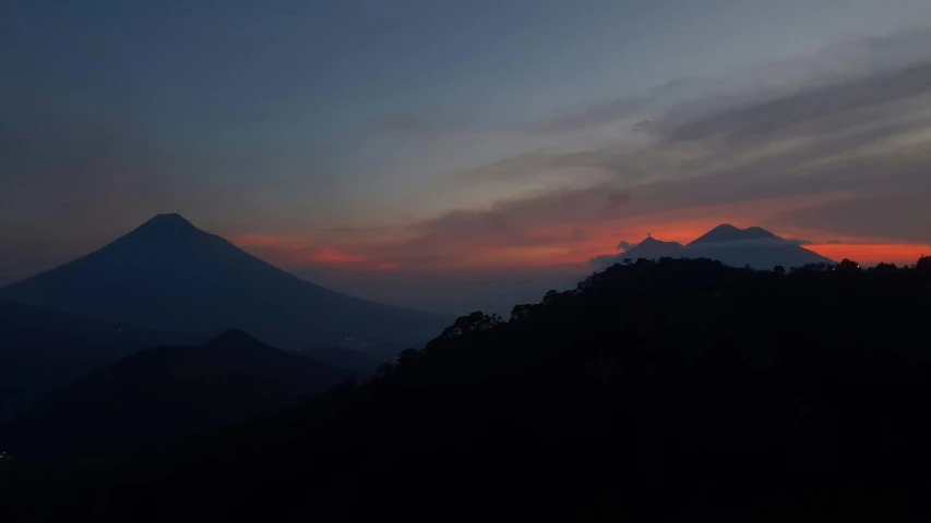 a sunset over a mountain with some clouds and red colored sky