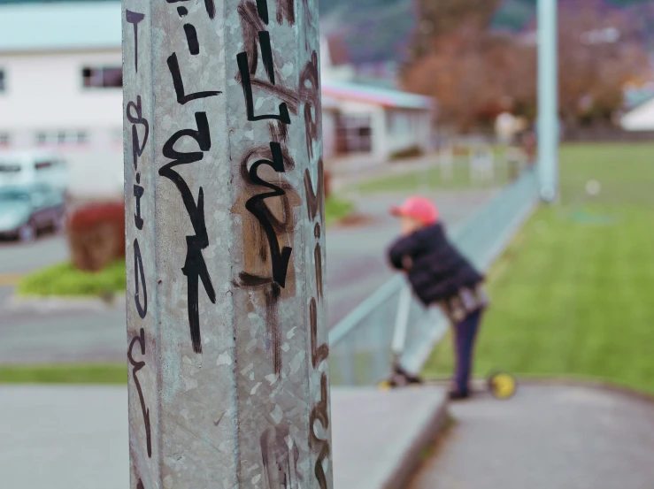 a boy standing next to a tall pole on a street