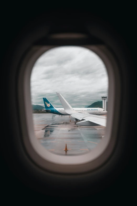 the view through an airplane window shows another plane taking off