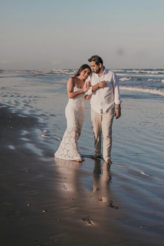 a couple standing on the beach in front of the ocean